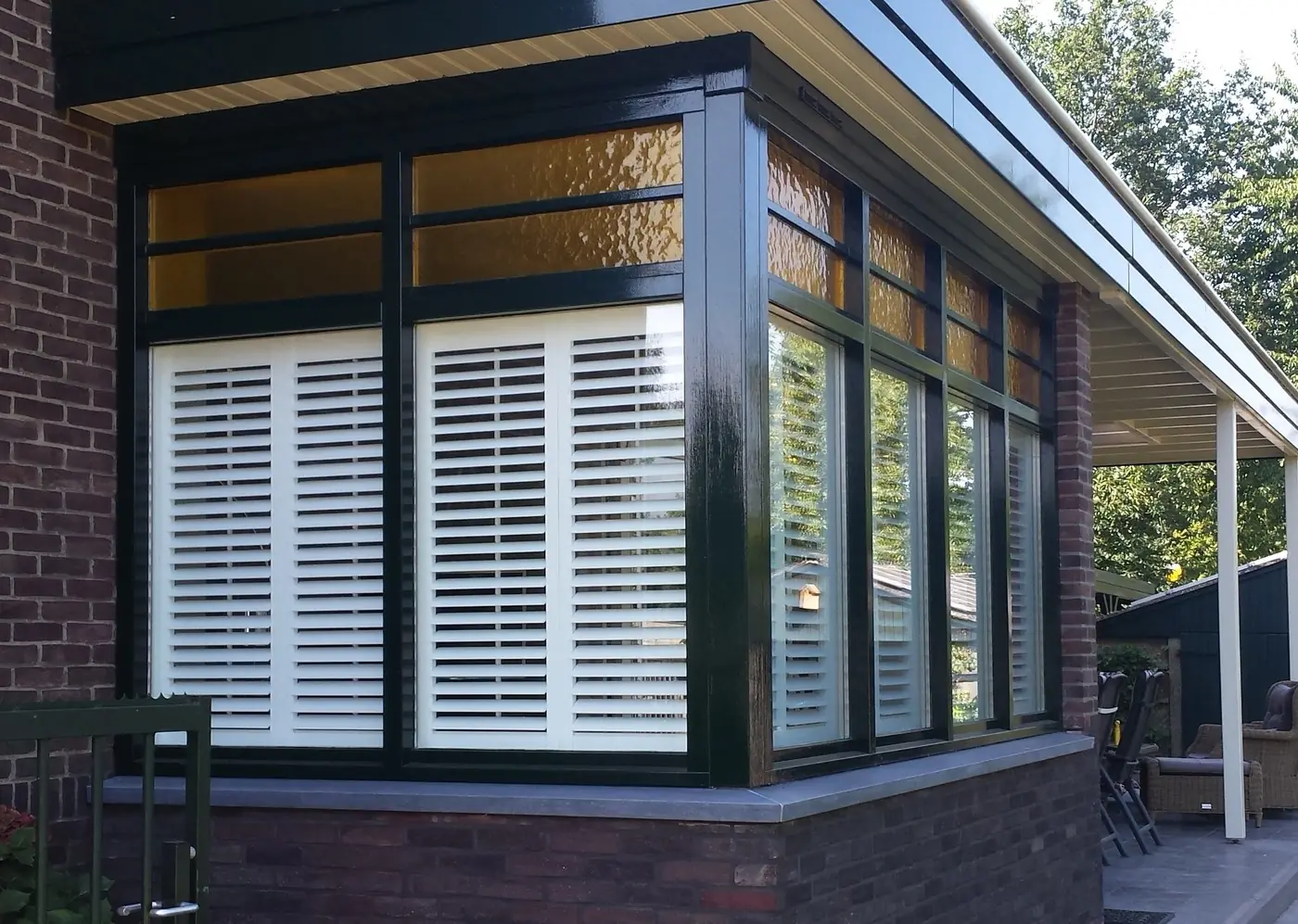 Serre met shutters achter de ramen, gezien vanaf de tuin